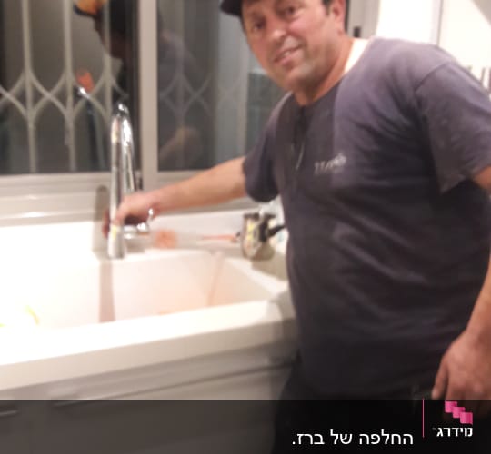 אדם ליד כיור מטבח עם ברז כרום